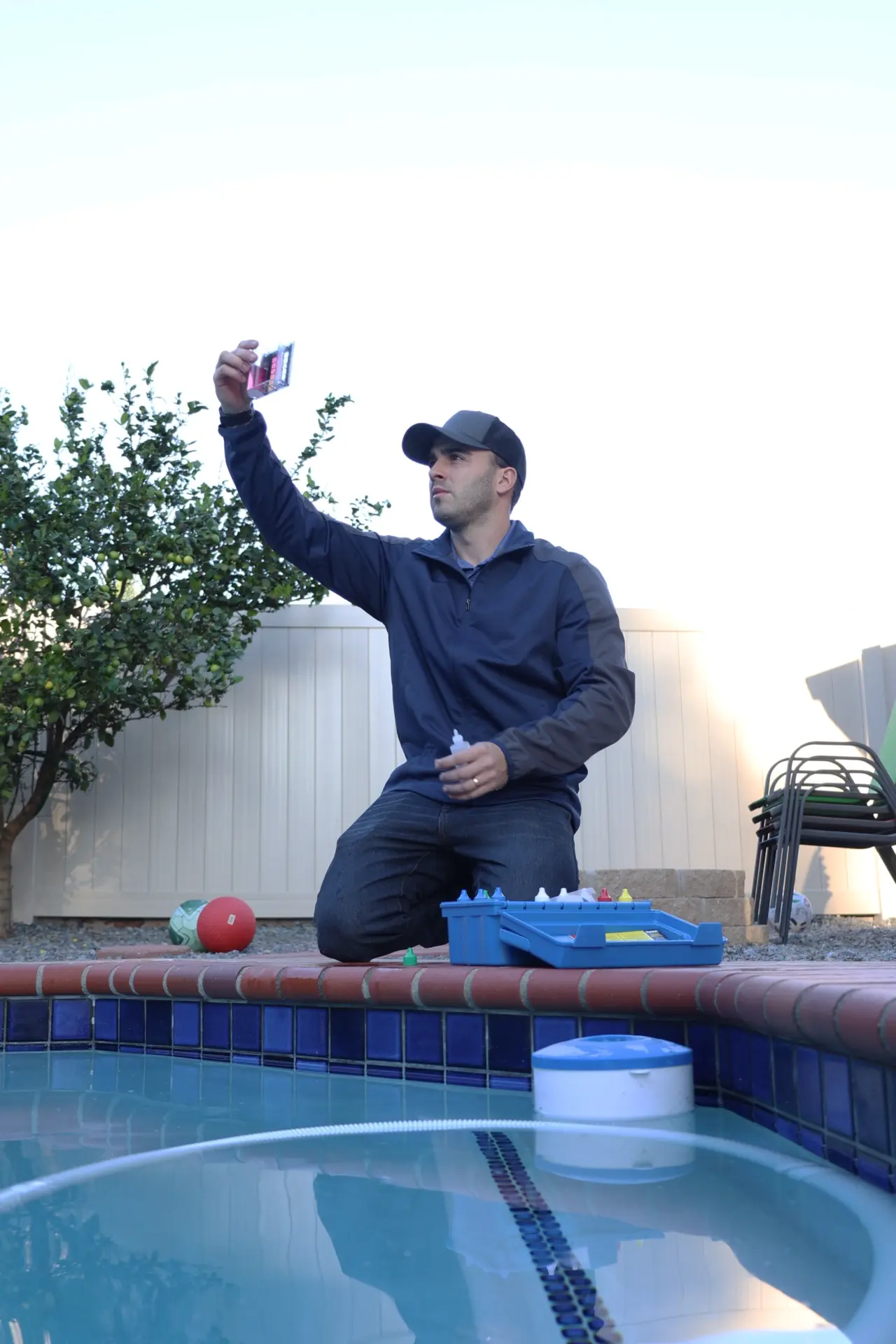 Technician reading a pool test strip at dusk